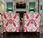 Two chairs with pink and white patterned backs face a fireplace in a living room.