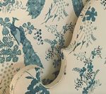 Cream fabric with teal peacock and floral print on curved chair back.