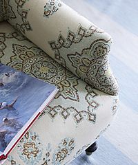 Armchair with patterned fabric, a book on the seat, and a light blue floor in the background.