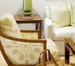 Living room with upholstered chair, cream sofa, side table with lamp, and tote bag.