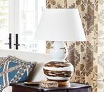 White table lamp with a brown and white ceramic base on a wooden nightstand.