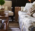 Living room with patterned chair, sofa with floral pattern, zebra print pillow, and wooden table.