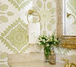 Bathroom with green patterned wallpaper, gold towel ring, and bouquet of white flowers.