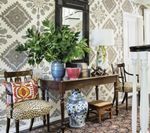 Entryway with patterned wallpaper, table, chairs, plants, and a mirror.