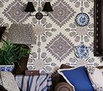 Wallpapered wall with decorative patterns, sconce, plates, and a sofa with pillows.