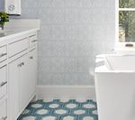Bathroom with white cabinets, blue patterned floor, light blue patterned walls, and a white tub.