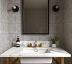 Bathroom vanity with marble countertop, gold fixtures, and black framed mirror.