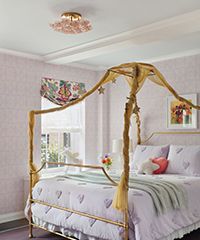 Bedroom with a gold canopy bed, lavender bedding, and floral wallpaper.