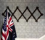 Brown wooden coat rack with US and Australian flags hanging on it.