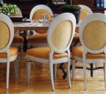 White-framed dining chairs with golden yellow upholstery around a table, set on a hardwood floor.