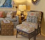 Living room with floral patterned chair and sofa, patterned ottoman, and lamps.