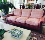 Pink upholstered sofa with dark wood trim, in a well-lit living room.