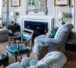 Living room with blue upholstered furniture, white fireplace, and trellis wallpaper.