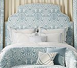 Bed with blue patterned headboard, matching bedding, and decorative pillows.