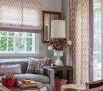 Cozy living room with floral patterned curtains and shades, a sofa, and a table lamp.