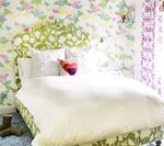 Bedroom with floral wallpaper and patterned headboard, bed with white bedding.