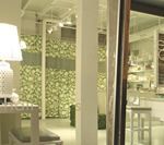 Interior of a store, featuring a white lamp on a table, floral wallpaper, and glass display windows.