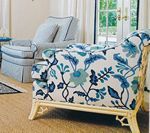 Floral patterned settee and solid blue armchair in a light-filled room.