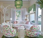 Living room with floral chairs, curved white couch, green chandelier, and pastel decor.
