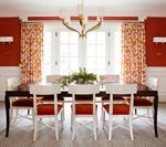 Dining room with red walls, white trim, table, chairs, and patterned curtains.