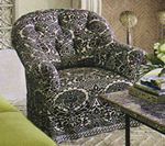 Tufted armchair in black and white paisley fabric, next to a small table.