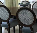 Dining chairs with oval backs, upholstered in patterned gray fabric, around a dark wooden table.