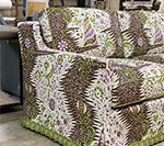 Couch with patterned upholstery featuring green, brown, and purple floral and geometric designs.