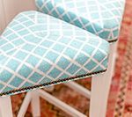 Two white bar stools with turquoise diamond pattern seats, black trim.