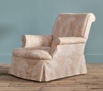 Upholstered armchair with light beige paisley pattern against a blue wall and wood floor.