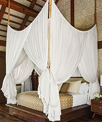 Bed with white canopy and wooden frame in a room.