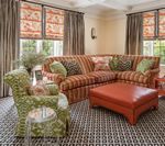 Living room with orange striped sofa, green patterned chair, and orange ottoman.