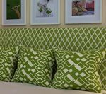 Green patterned headboard and pillows, framed photos above.