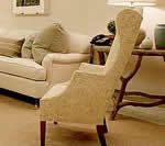 Cream-colored wingback chair in a living room, near a sofa and side table with decor.