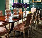 Dining room with dark wooden table, upholstered chairs, and purple flowers.
