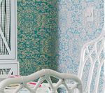 Two wallpaper samples, teal and light blue floral patterns, next to a white chair.