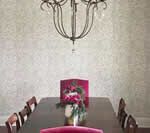 Dining room with chandelier, long dark wood table, and magenta chairs. A floral centerpiece sits on the table.