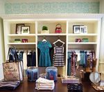 Clothing store interior with dresses on hangers and shelves with accessories.