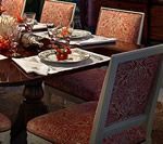 Dining table set for a meal with four chairs, cream-colored frames, and patterned upholstery.