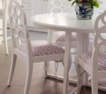 White round dining table with matching chairs, patterned cushions, and a blue and white vase.