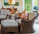 Wicker chair and ottoman with patterned cushions, in a sunlit living room.