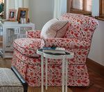 Floral armchair with a side table, a white storage unit, and a pillow.
