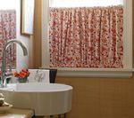 Kitchen with a white sink, floral curtain, and window.