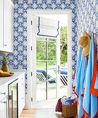Blue and white patterned room with open door to outdoor pool area; towels and hat hanging.