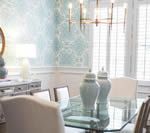 Elegant dining room with glass table, patterned wallpaper, and light blue accents.