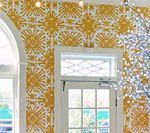 Yellow patterned wallpaper on a white-framed wall with a window, part of a room.