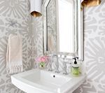 Bathroom with white sink, mirror, and patterned gray wallpaper; a towel hangs on the left.