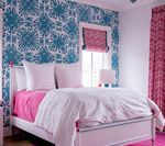 Bedroom with blue patterned wallpaper, pink bed linens, and pink curtains.