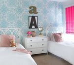 Bedroom with white beds, dresser, blue patterned wallpaper, pink accents, and 