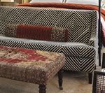 Sofa with geometric black and white patterned back, red patterned ottoman, and accent pillows.