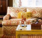 Couch with ornate pattern, coffee table, and decorative items. Soft, warm colors create a cozy interior.